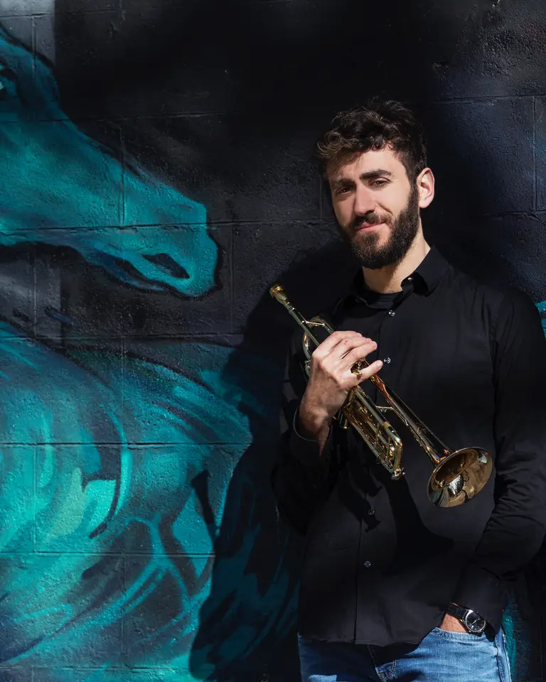 Alessandro Bottacchiari con la tromba davanti a un murale blu